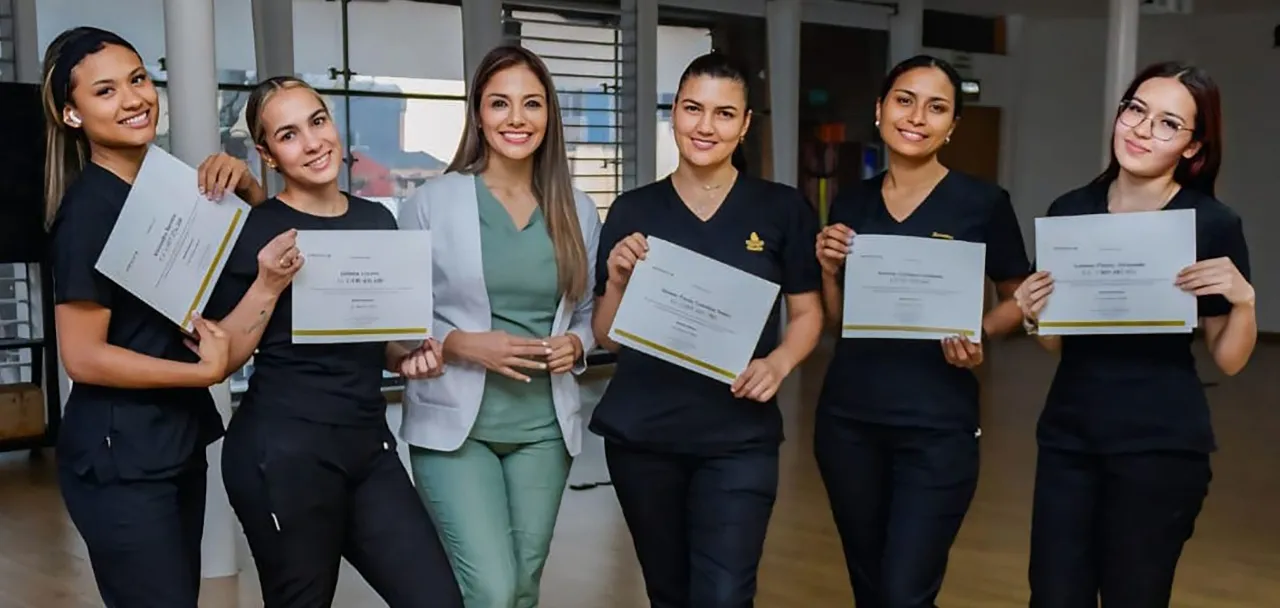 Seis alumnas de Aprendizaje Estético con uniforme, sosteniendo sus certificados